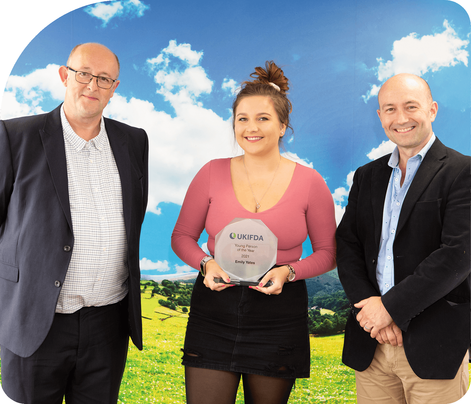 A photo of 3 individuals of which one of them is Emily Yates, transport planner at craggs energy holding a UKIFDA trophy for winning young person of the year award.