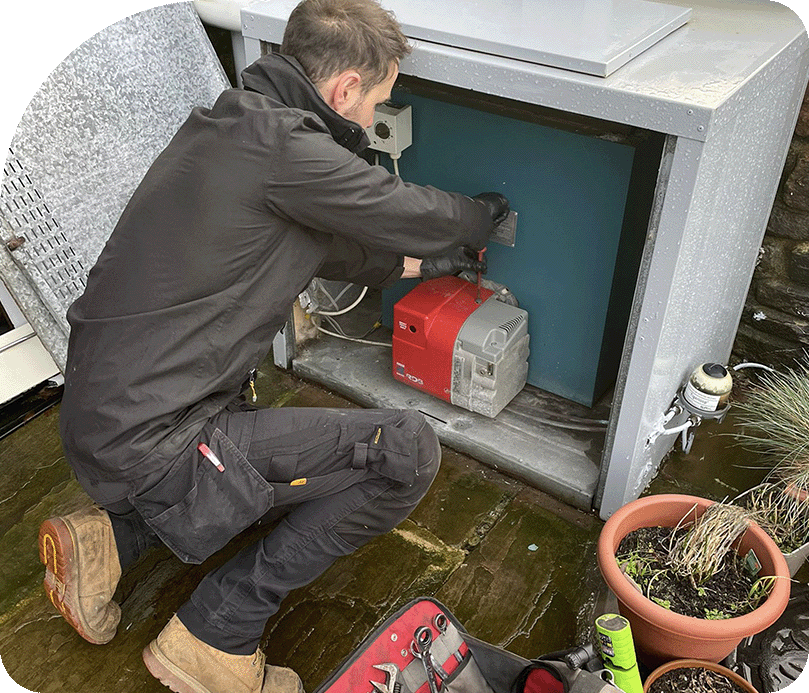 Craggs Energy oil boiler service technician Neil servicing an oil boiler outside with tools.