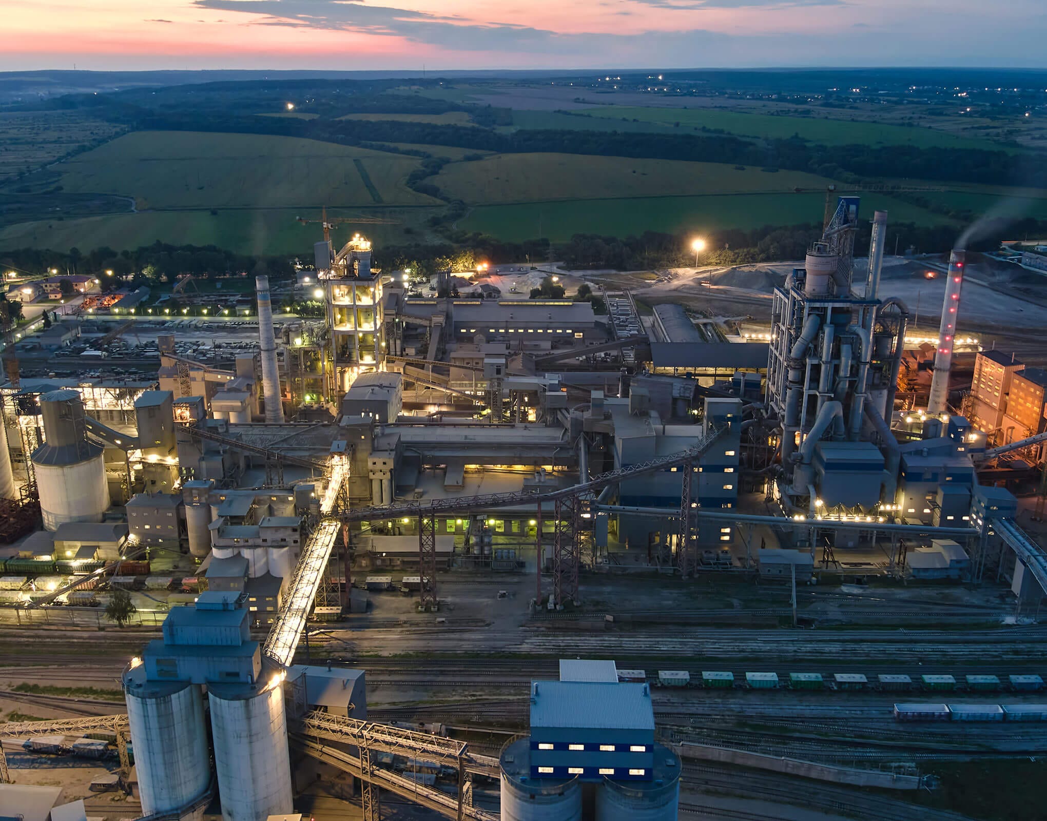 Aerial photograph of a large industrial facility during sunset, showing various structures and machinery.