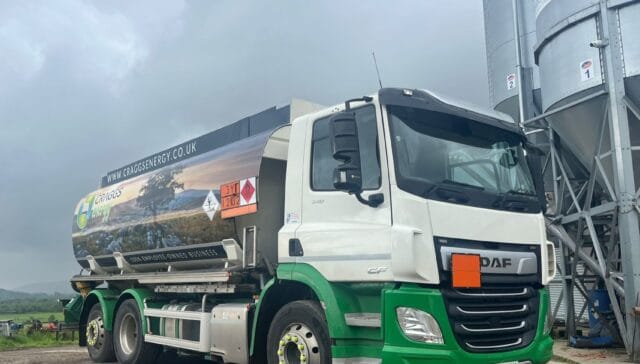 A DAF tanker truck parked near industrial silos under cloudy skies, used for transporting agricultural products.